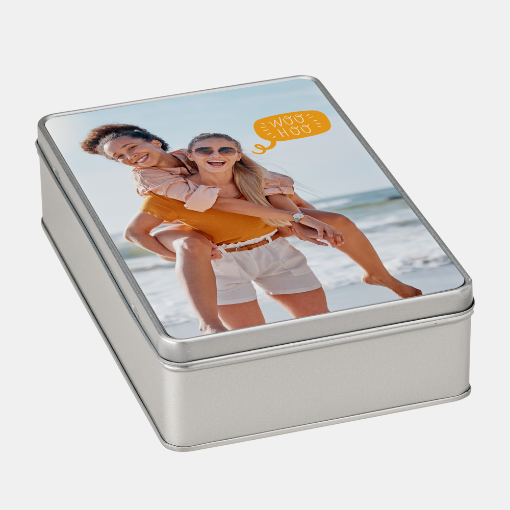 Eine silberne Fotodose zeigt zwei lachende Menschen am Meer, einer trägt den anderen auf dem Rücken.
